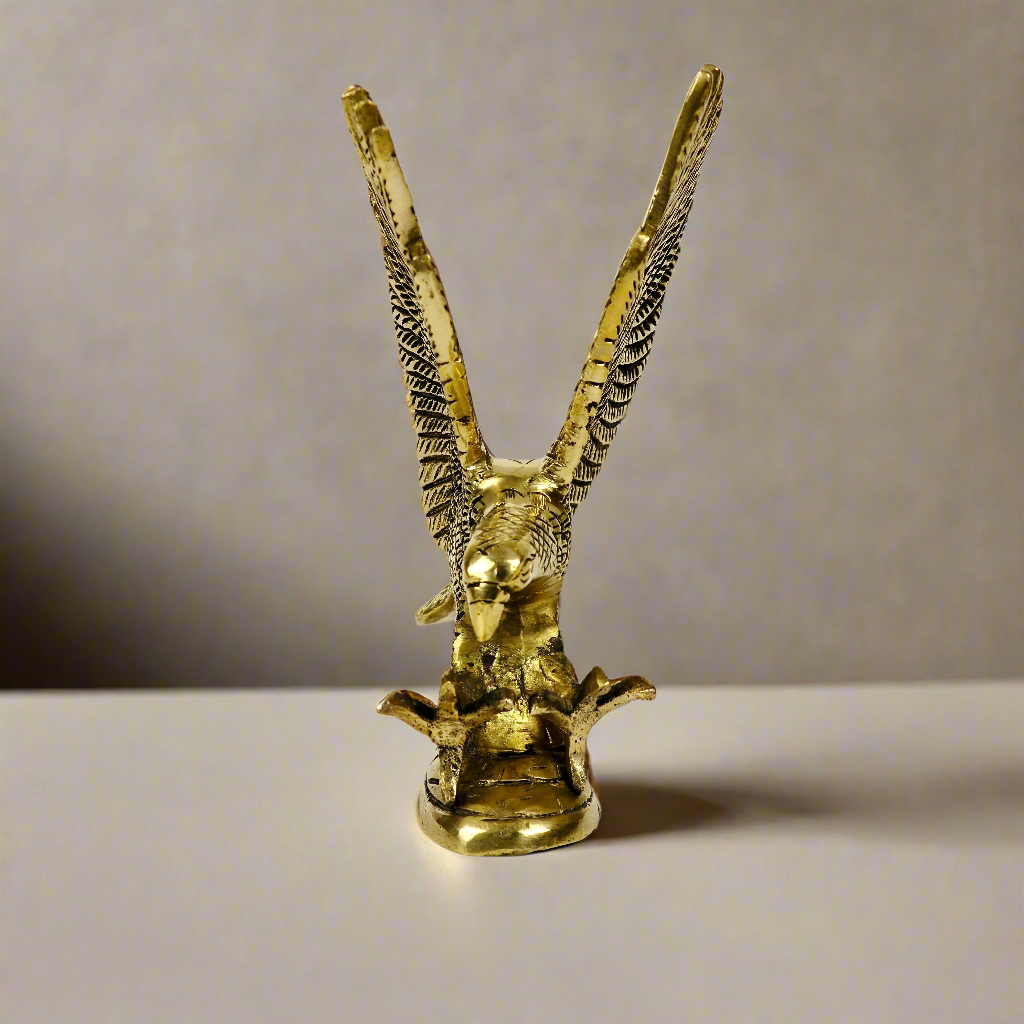 Product image of a Brass Eagle figurine from Indian Impressions, depicting the eagle in a poised stance with outspread wings. Crafted with intricate detailing and a polished brass finish, this piece symbolizes strength, protection, and vision, making it ideal for Vastu, home décor, or gifting.