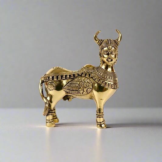 Product image of a Brass Kamdhenu Cow from Indian Impressions, intricately crafted with detailed carvings. The cow is depicted in a standing posture, symbolizing prosperity, abundance, and spiritual significance. Finished in polished brass, this piece is ideal for Vastu, spiritual practices, home décor, or gifting to bring positive energy and blessings to any space.