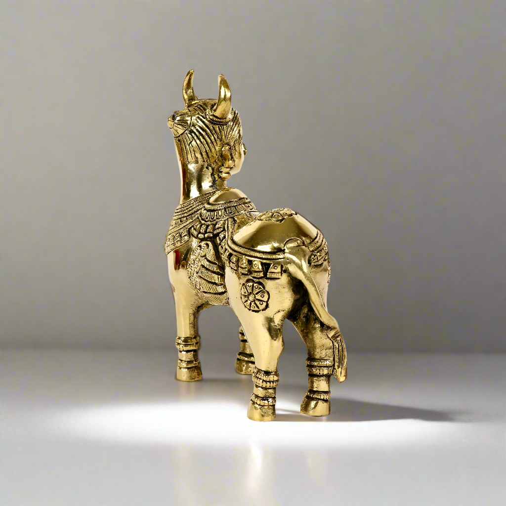 Product image of a Brass Kamdhenu Cow from Indian Impressions, intricately crafted with detailed carvings. The cow is depicted in a standing posture, symbolizing prosperity, abundance, and spiritual significance. Finished in polished brass, this piece is ideal for Vastu, spiritual practices, home décor, or gifting to bring positive energy and blessings to any space.