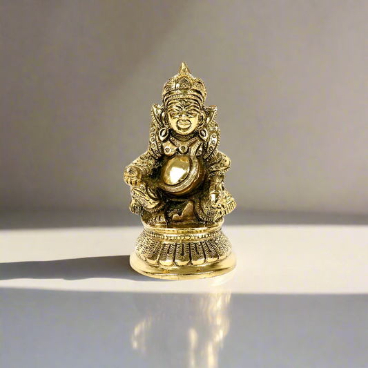 Product image of a Brass Kuber Idol from Indian Impressions, featuring Lord Kuber, the deity of wealth, seated gracefully with a pot of treasures. The idol is intricately crafted with fine details and a polished brass finish, making it perfect for Vastu, spiritual practices, home décor, or gifting to attract prosperity and abundance.