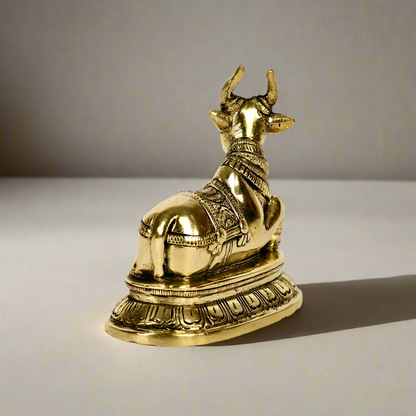 Product image of a Brass Nandi Ji from Indian Impressions, depicting the sacred bull in a seated posture with intricate detailing. Crafted from polished brass, this idol symbolizes devotion, strength, and positivity. Ideal for Vastu, spiritual practices, home décor, or gifting to bring blessings and harmony to any space.