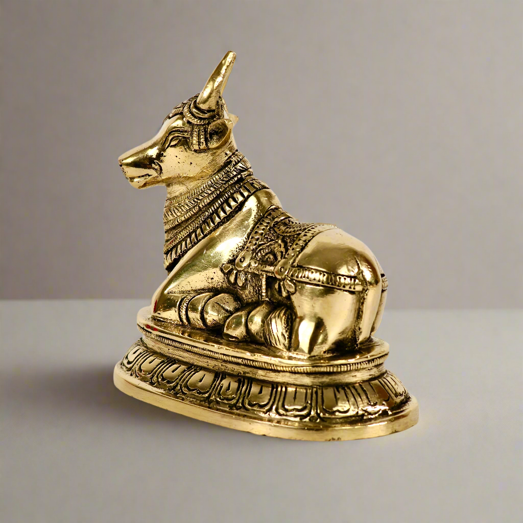 Product image of a Brass Nandi Ji from Indian Impressions, depicting the sacred bull in a seated posture with intricate detailing. Crafted from polished brass, this idol symbolizes devotion, strength, and positivity. Ideal for Vastu, spiritual practices, home décor, or gifting to bring blessings and harmony to any space.