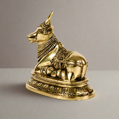 Product image of a Brass Nandi Ji from Indian Impressions, depicting the sacred bull in a seated posture with intricate detailing. Crafted from polished brass, this idol symbolizes devotion, strength, and positivity. Ideal for Vastu, spiritual practices, home décor, or gifting to bring blessings and harmony to any space.