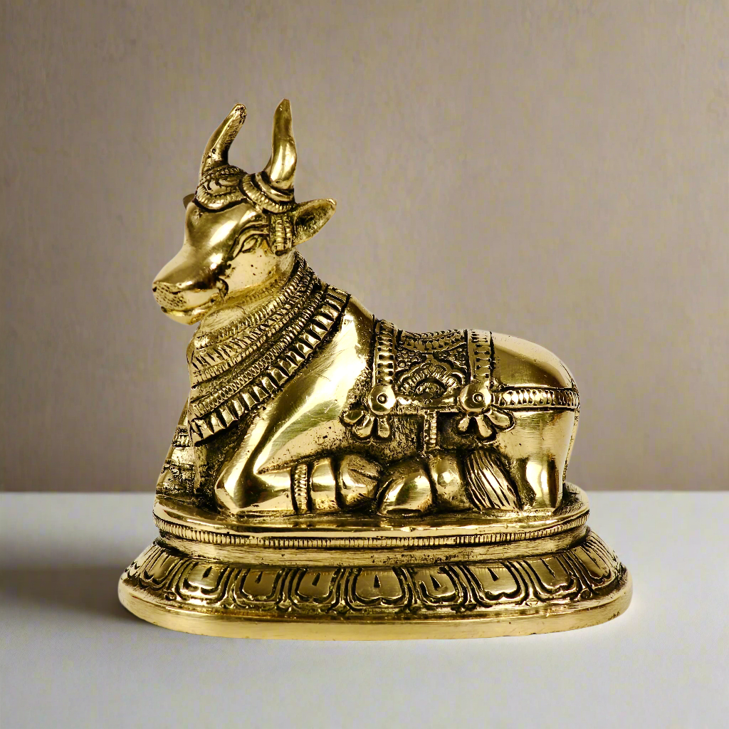 Product image of a Brass Nandi Ji from Indian Impressions, depicting the sacred bull in a seated posture with intricate detailing. Crafted from polished brass, this idol symbolizes devotion, strength, and positivity. Ideal for Vastu, spiritual practices, home décor, or gifting to bring blessings and harmony to any space.