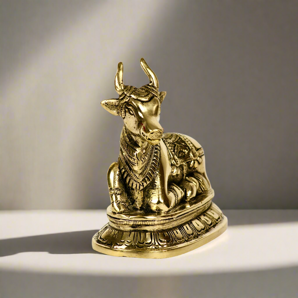 Product image of a Brass Nandi Ji from Indian Impressions, depicting the sacred bull in a seated posture with intricate detailing. Crafted from polished brass, this idol symbolizes devotion, strength, and positivity. Ideal for Vastu, spiritual practices, home décor, or gifting to bring blessings and harmony to any space.