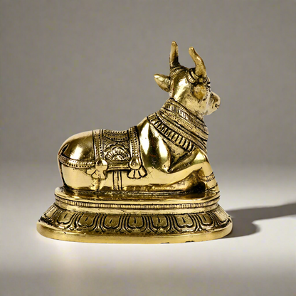 Product image of a Brass Nandi Ji from Indian Impressions, depicting the sacred bull in a seated posture with intricate detailing. Crafted from polished brass, this idol symbolizes devotion, strength, and positivity. Ideal for Vastu, spiritual practices, home décor, or gifting to bring blessings and harmony to any space.