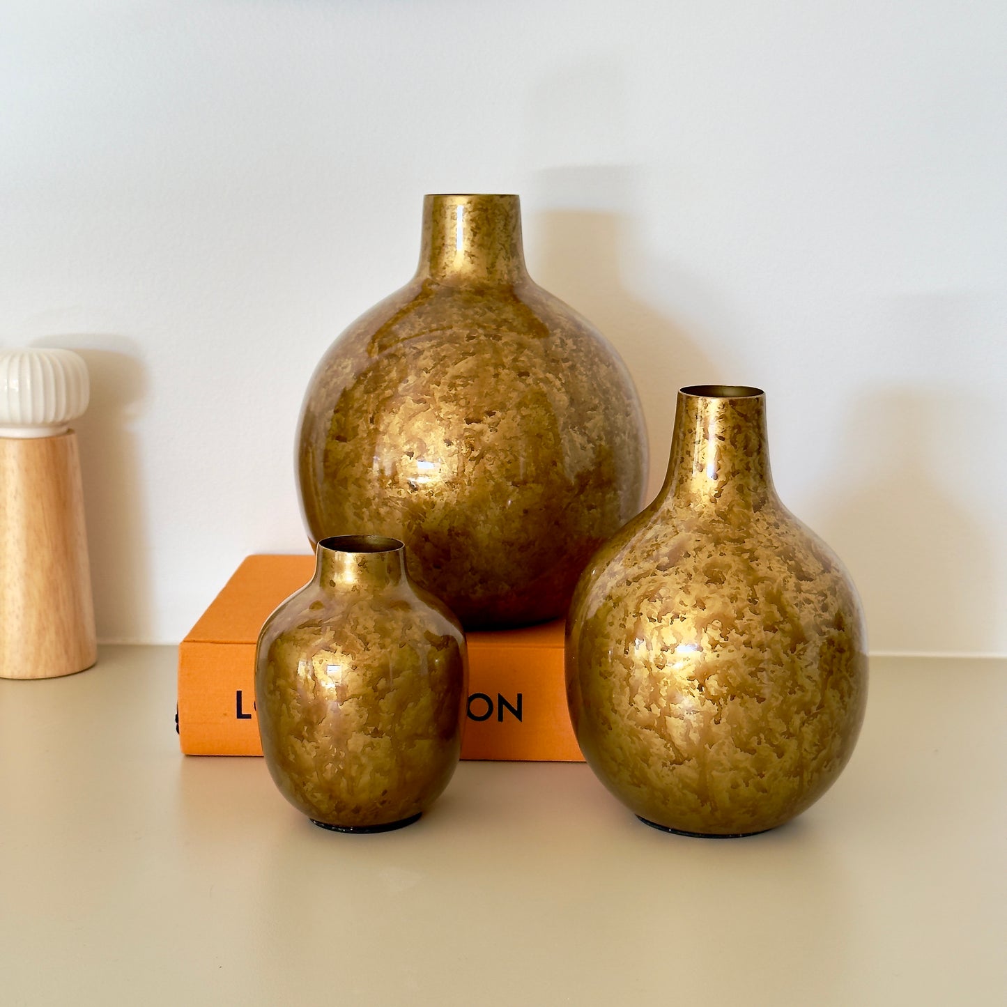 Product image of the Metal Bud Vase Set of 3 in Antique Gold from Indian Impressions, featuring a trio of elegantly designed vases with a vintage gold finish. Perfect for displaying single stems or as standalone décor pieces, these vases are ideal for Vastu, home décor, or gifting, adding a sophisticated and timeless touch to any space.