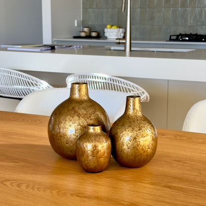 Product image of the Metal Bud Vase Set of 3 in Antique Gold from Indian Impressions, featuring a trio of elegantly designed vases with a vintage gold finish. Perfect for displaying single stems or as standalone décor pieces, these vases are ideal for Vastu, home décor, or gifting, adding a sophisticated and timeless touch to any space.