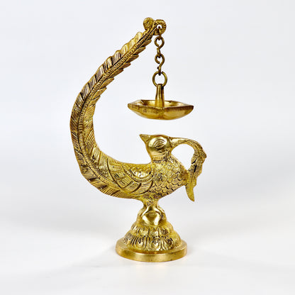 Image of a brass Bulbul Diya, featuring an elegant bird-shaped design with intricate carvings. The diya showcases a deep bowl for holding oil or ghee, complemented by a polished brass finish that adds a traditional charm. Perfect for spiritual rituals, festive décor, or gifting, this diya brings a touch of grace and serenity to any space.