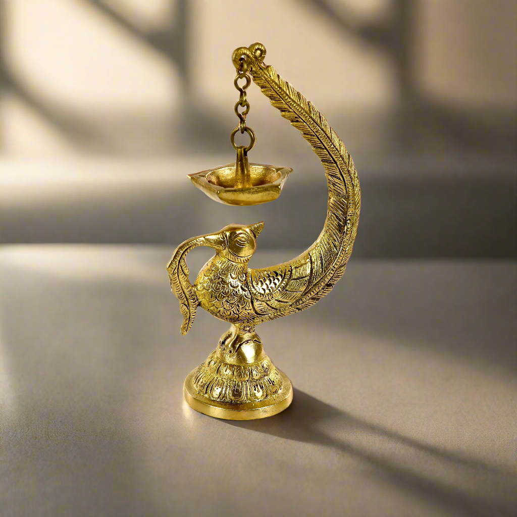 Image of a brass Bulbul Diya, featuring an elegant bird-shaped design with intricate carvings. The diya showcases a deep bowl for holding oil or ghee, complemented by a polished brass finish that adds a traditional charm. Perfect for spiritual rituals, festive décor, or gifting, this diya brings a touch of grace and serenity to any space.