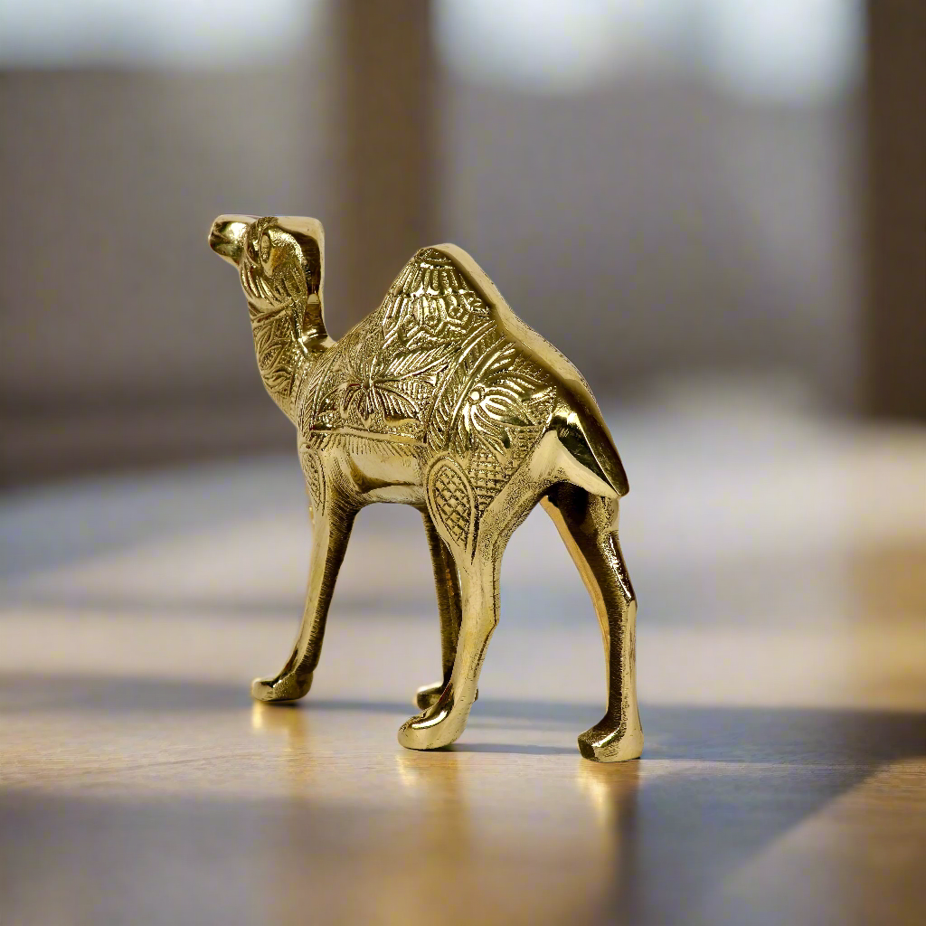 Product image of a Brass Camel figurine from Indian Impressions, intricately crafted with detailed features. The camel is depicted in a standing posture, symbolizing endurance and strength. Finished with a polished brass shine, this decorative piece is ideal for Vastu, home décor, or gifting.