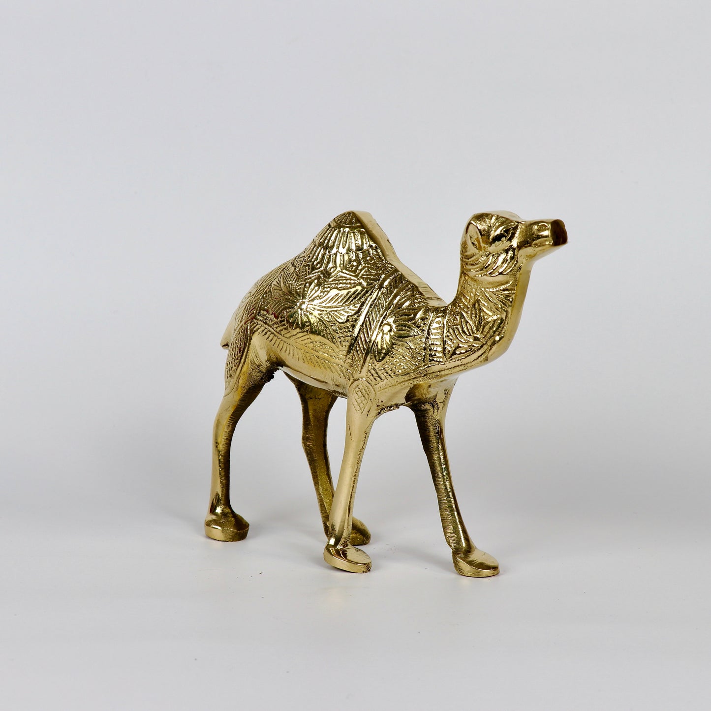 Product image of a Brass Camel figurine from Indian Impressions, intricately crafted with detailed features. The camel is depicted in a standing posture, symbolizing endurance and strength. Finished with a polished brass shine, this decorative piece is ideal for Vastu, home décor, or gifting.