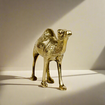 Product image of a Brass Camel figurine from Indian Impressions, intricately crafted with detailed features. The camel is depicted in a standing posture, symbolizing endurance and strength. Finished with a polished brass shine, this decorative piece is ideal for Vastu, home décor, or gifting.