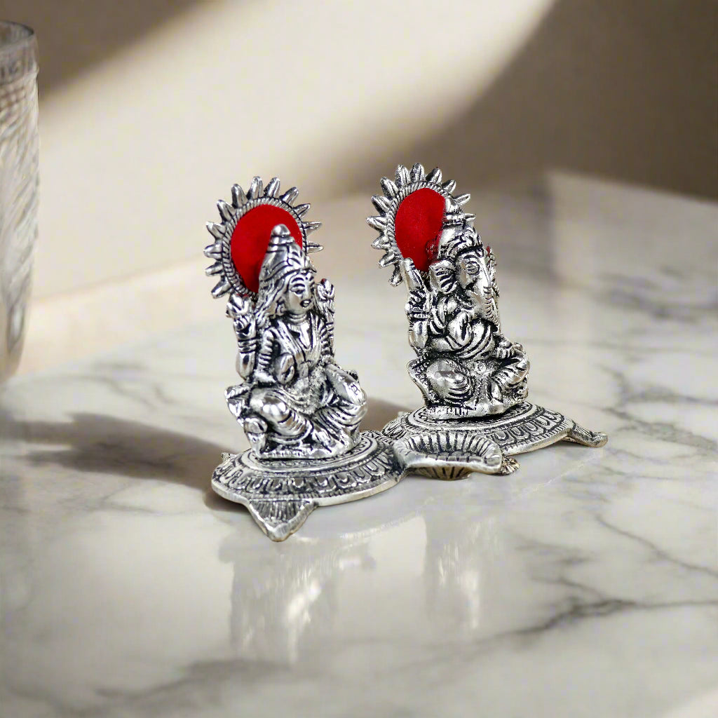 Product image of a Ganesh Lakshmi Gift Set in Silver from Indian Impressions, featuring intricately crafted idols of Lord Ganesha and Goddess Lakshmi. The idols are made with a polished silver finish, symbolizing prosperity, wisdom, and blessings. Ideal for gifting, home décor, or spiritual practices, this set brings divine energy and elegance to any space.