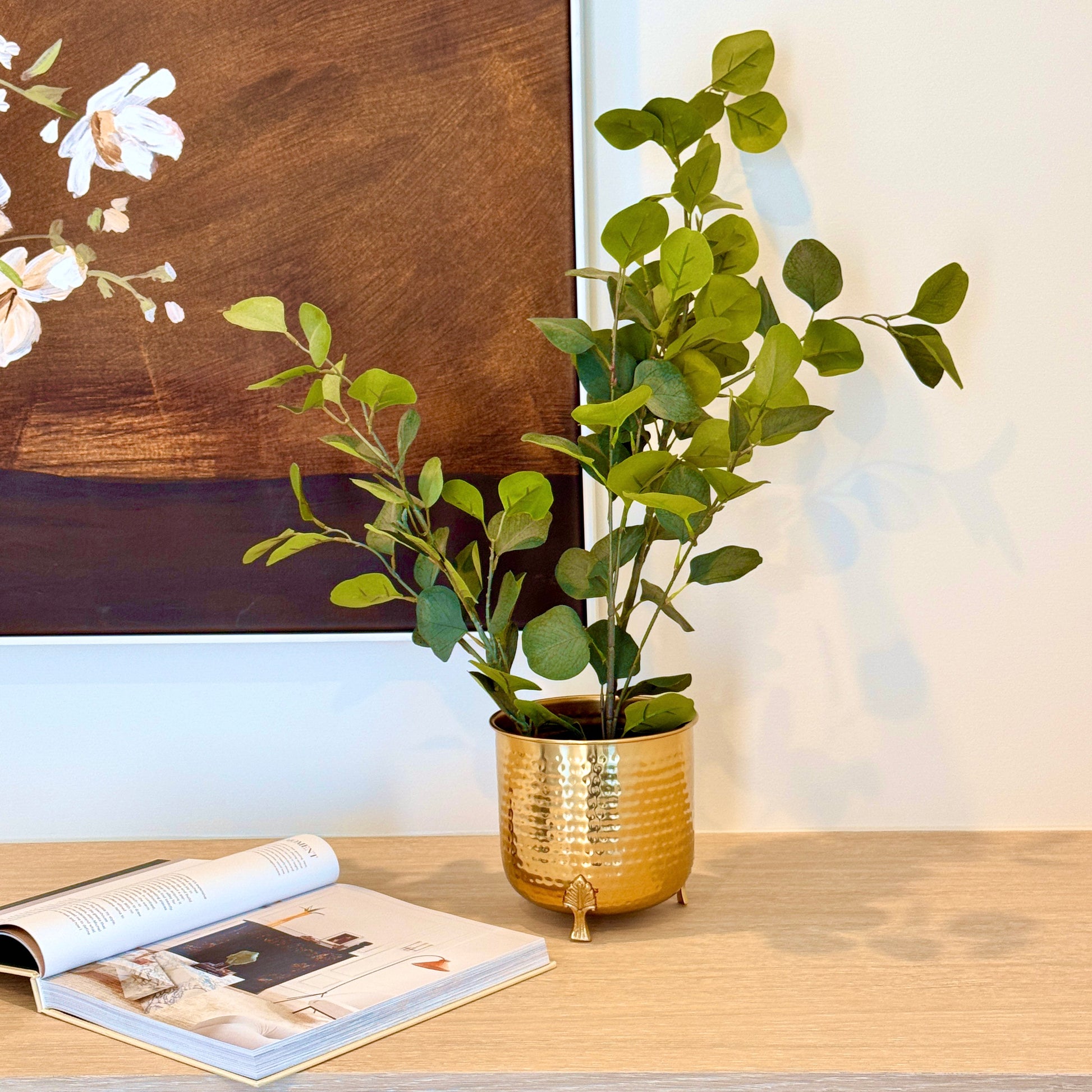 Product image of a Hammered Leaf Leg Planter in Gold from Indian Impressions, featuring a unique hammered texture and a leaf-patterned design. The planter comes with sturdy legs, crafted for elegance and stability. Ideal for enhancing Vastu energy, home décor, or gifting, this piece adds a modern yet traditional charm to any space.