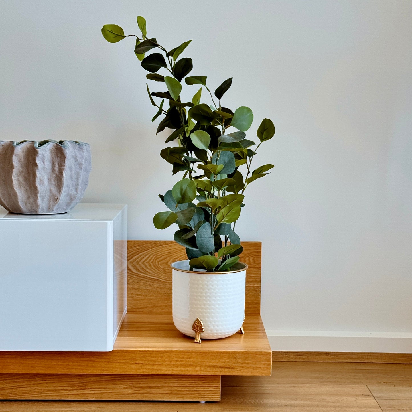 Product image of a Metal Hammered Gold Rim Leaf Leg Planter in White from Indian Impressions, featuring a sleek white body with a hammered texture and a gold rim for an elegant finish. Supported by sturdy leaf-patterned legs, this planter is ideal for enhancing Vastu energy, modern home décor, or gifting, adding sophistication to any space.