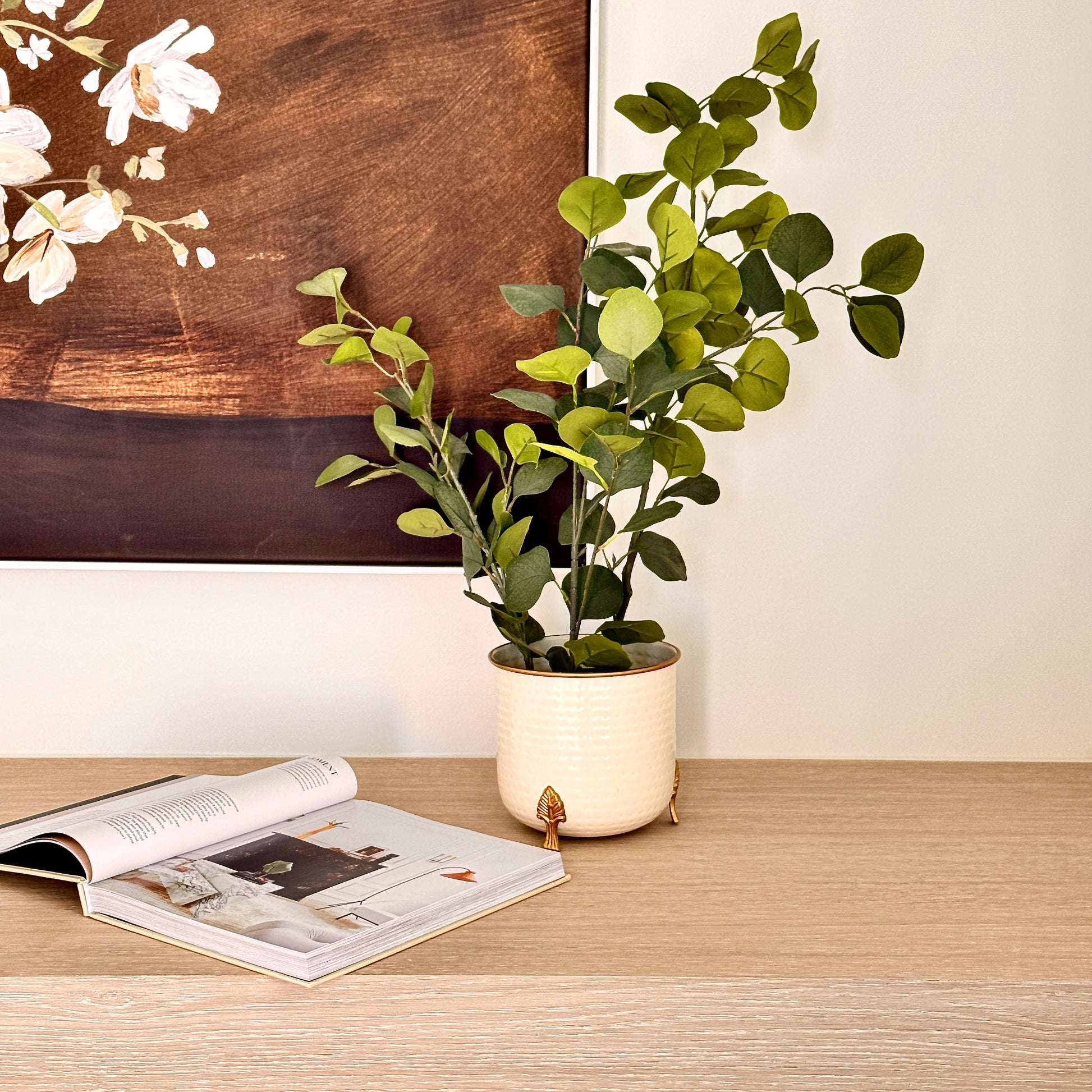 Product image of a Metal Hammered Gold Rim Leaf Leg Planter in White from Indian Impressions, featuring a sleek white body with a hammered texture and a gold rim for an elegant finish. Supported by sturdy leaf-patterned legs, this planter is ideal for enhancing Vastu energy, modern home décor, or gifting, adding sophistication to any space.