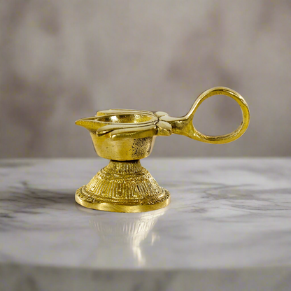 Product image of a Brass Lotus Diya with Handle from Indian Impressions, featuring a beautifully crafted lotus design and a sturdy handle for ease of use. Made from polished brass, this diya is ideal for Vastu, spiritual rituals, home décor, or gifting, symbolizing purity, positivity, and divine light.