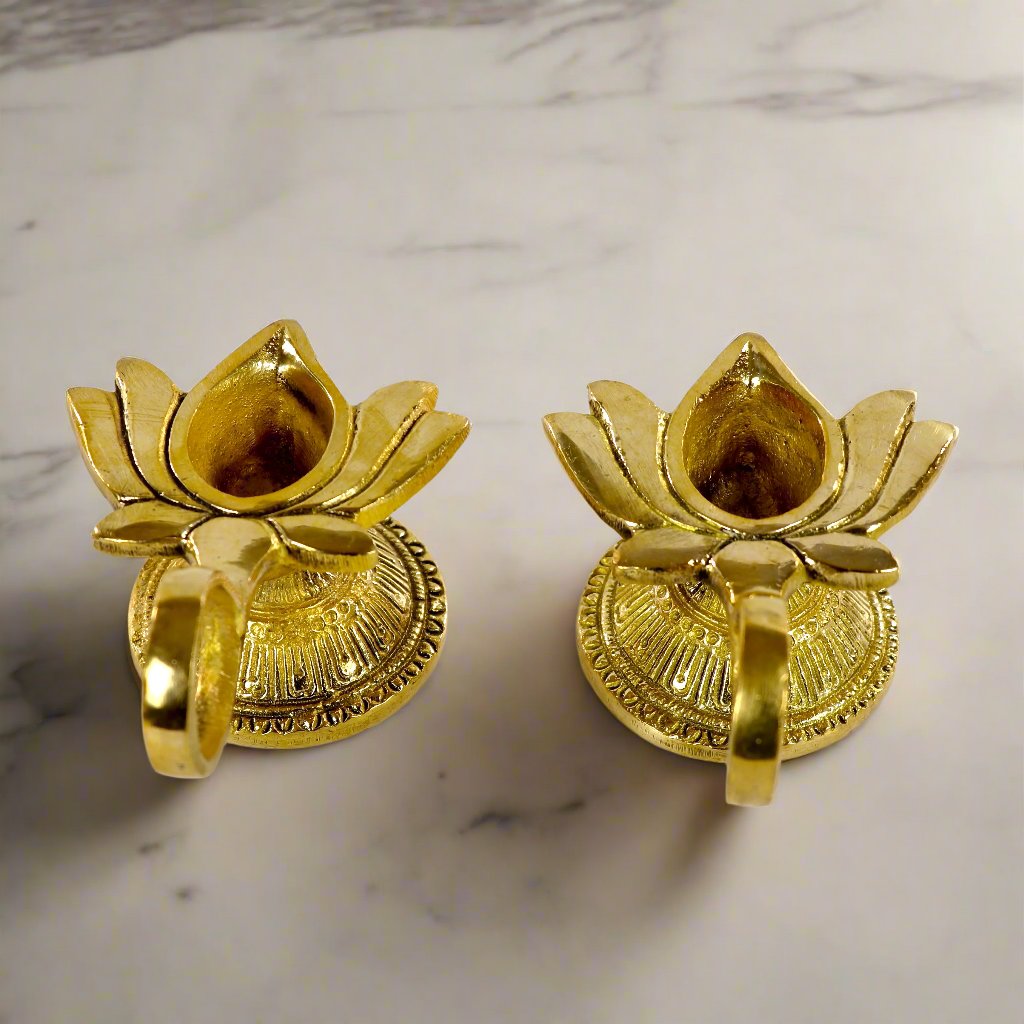 Product image of a Brass Lotus Diya with Handle from Indian Impressions, featuring a beautifully crafted lotus design and a sturdy handle for ease of use. Made from polished brass, this diya is ideal for Vastu, spiritual rituals, home décor, or gifting, symbolizing purity, positivity, and divine light.