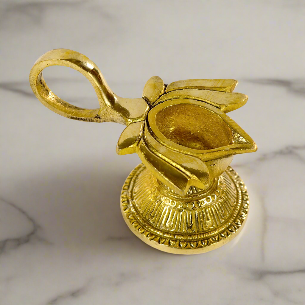 Product image of a Brass Lotus Diya with Handle from Indian Impressions, featuring a beautifully crafted lotus design and a sturdy handle for ease of use. Made from polished brass, this diya is ideal for Vastu, spiritual rituals, home décor, or gifting, symbolizing purity, positivity, and divine light.