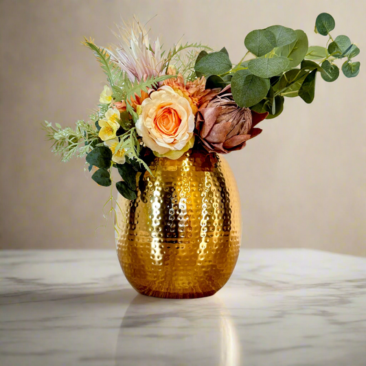 Product image of the Oval Vase Hammered Gold from Indian Impressions, featuring a sleek oval design with a textured hammered finish. Crafted with a polished gold-tone, this vase is perfect for displaying flowers or as a standalone décor piece. Ideal for Vastu, home décor, or gifting, adding elegance and sophistication to any space.