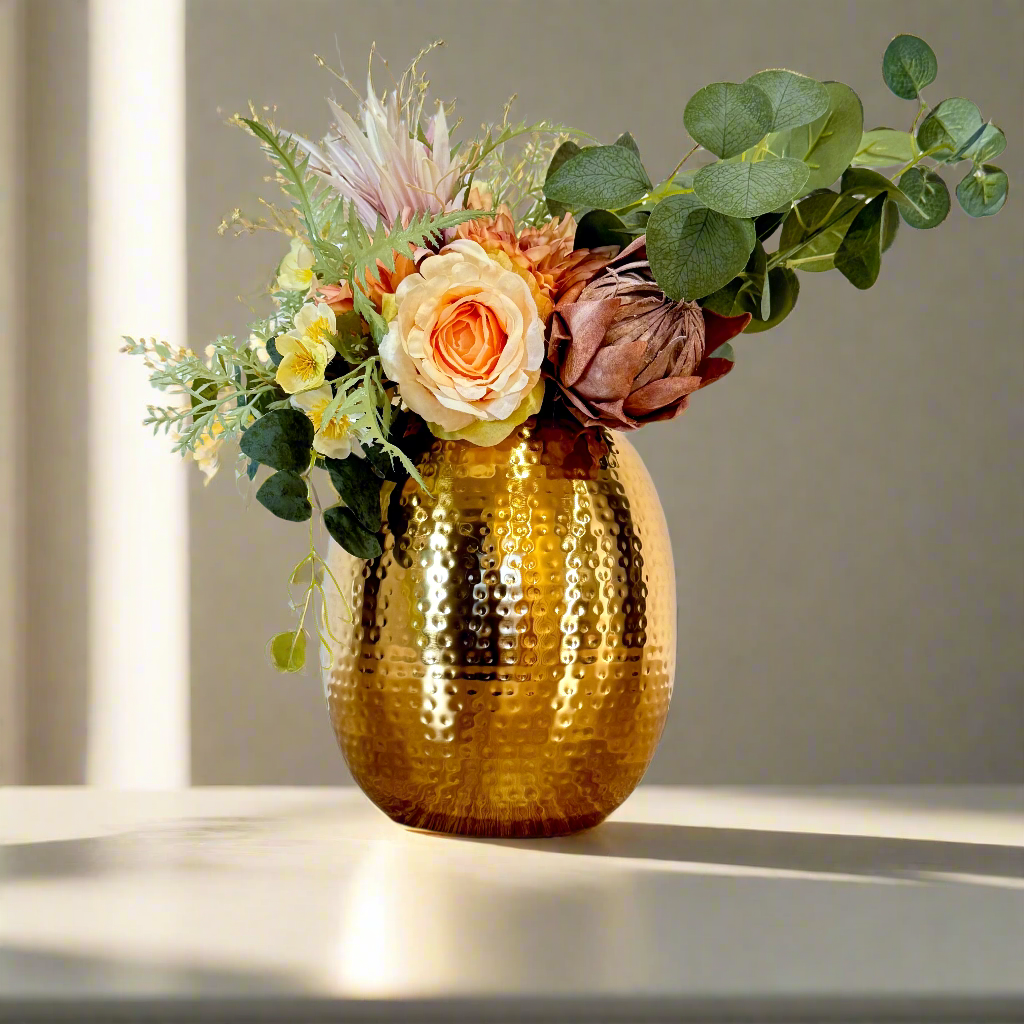 Product image of the Oval Vase Hammered Gold from Indian Impressions, featuring a sleek oval design with a textured hammered finish. Crafted with a polished gold-tone, this vase is perfect for displaying flowers or as a standalone décor piece. Ideal for Vastu, home décor, or gifting, adding elegance and sophistication to any space.