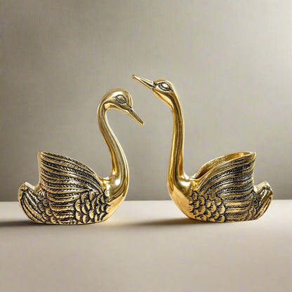 Product image of the Swan Figurine Candle Holder Pair in Gold from Indian Impressions, showcasing two intricately crafted swan-shaped candle holders with a polished gold finish. Ideal for holding candles, this elegant pair is perfect for Vastu, home décor, festive occasions, or gifting, adding sophistication and charm to any space.