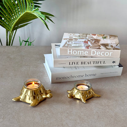 Product image of the Turtle Candle Holder Pair in Gold from Indian Impressions, featuring two beautifully crafted turtle-shaped candle holders with a polished gold finish. Ideal for holding candles, this pair symbolizes stability and longevity. Perfect for Vastu, home décor, or gifting, adding elegance and positive energy to any space.